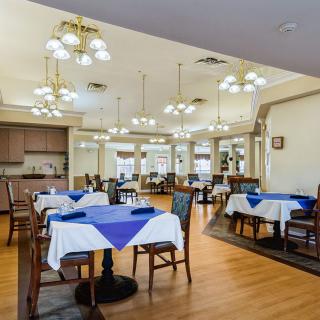 An inviting dining room with tables set with blue tablecloths and elegant lighting.