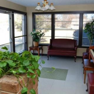 A quiet waiting room with chairs, a sofa, and potted plants by the windows.