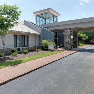 A modern building with a covered entrance and well-maintained landscaping along the driveway.