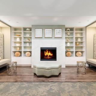 A modern living room with a central fireplace, surrounded by shelves and contemporary seating.