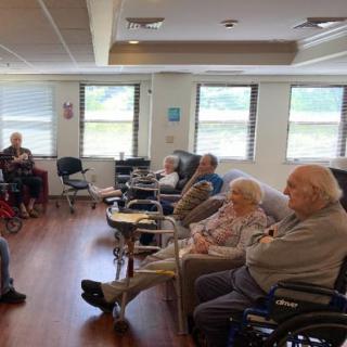 A group of elderly individuals seated in wheelchairs inside a nursing home.