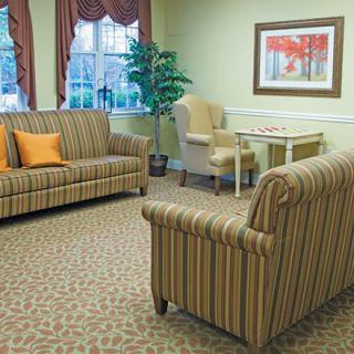 A cozy living room with striped sofas, a small table with chairs, and a decorative painting on the wall.