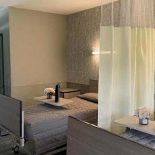 A tidy hospital room featuring a bed, curtain divider, and minimalistic decor.