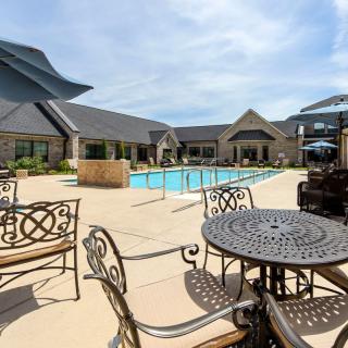 A luxurious outdoor pool area with elegant patio furniture under a sunny sky.