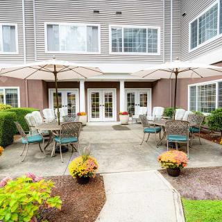 A welcoming outdoor patio area with tables, chairs, and umbrellas in a landscaped garden setting.