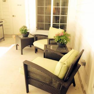 A cozy patio setting with cushioned chairs, a table, and decorative plants.