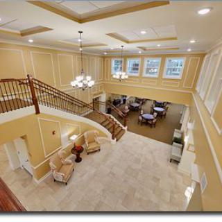A spacious interior view featuring a grand staircase, comfortable seating area, and elegant lighting.