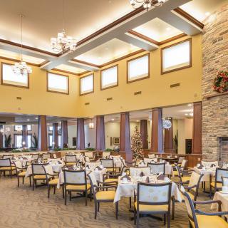 An elegantly decorated dining area with neatly arranged tables and chairs, illuminated by soft lighting.