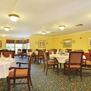 A spacious dining area with neatly arranged tables and chairs, set in a warmly decorated interior.