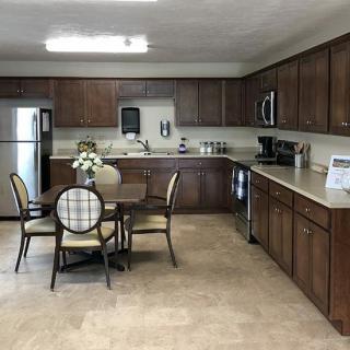 A modern kitchen interior with wooden cabinets, a table, and appliances.