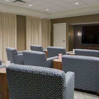 A modern conference room with patterned chairs arranged towards a large television.