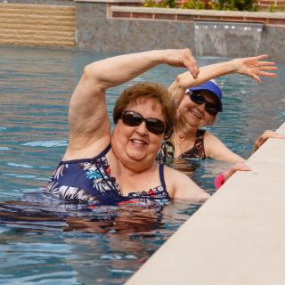 Two women enjoying their time in a swimming pool, posing with playful gestures.
