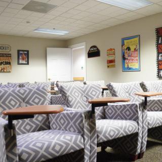 An empty waiting room with patterned chairs and colorful posters on the walls.