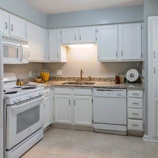 A modern kitchen with white cabinets, a stove, sink, and dishwasher.