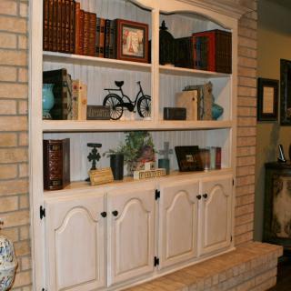 A vintage white bookshelf filled with books and decorative items in a cozy home setting.
