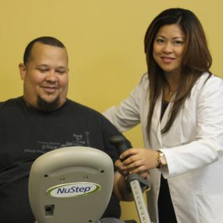 A therapist assists a patient with an exercise machine.