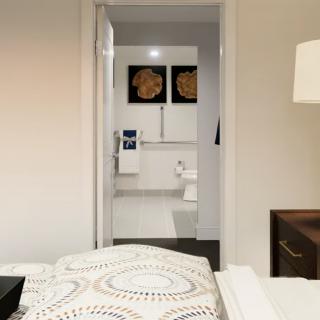 A modern bedroom with a view into an adjoining bathroom, featuring contemporary decor.