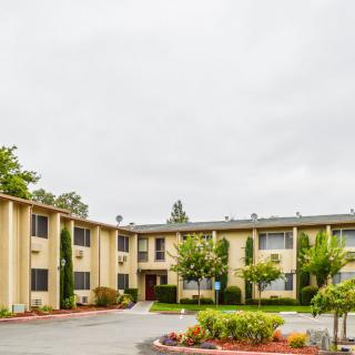 A residential apartment building with well-maintained landscaping under a cloudy sky.