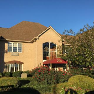 A large suburban house with a well-maintained garden on a sunny day.