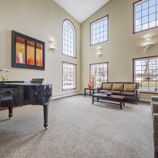 A spacious living room with high ceilings, featuring a grand piano and modern furnishings.