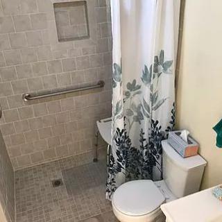 A small bathroom with a shower area and a floral shower curtain.