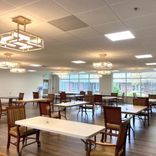 An empty dining area with elegant chandeliers and neatly arranged tables and chairs.