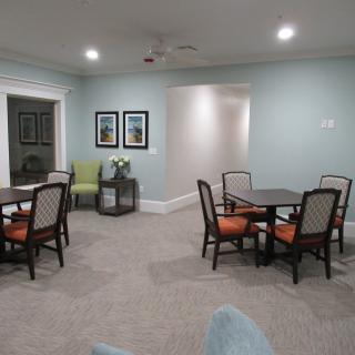 A cozy living room with tables and chairs arranged neatly on a carpeted floor.
