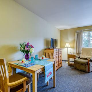 A cozy living room with a dining table set, TV, and comfortable seating by the window.