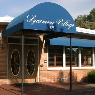 Entrance to Sycamore Village with blue awning.