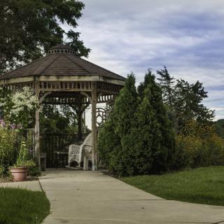 A serene garden featuring a wooden gazebo along a paved pathway.