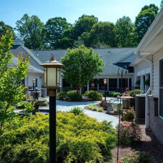 A beautifully landscaped outdoor area with lush greenery and a well-maintained pathway surrounded by buildings.
