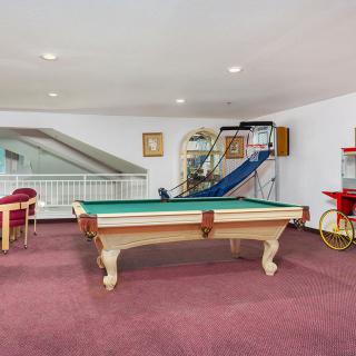 A spacious game room featuring a billiards table, indoor slide, and popcorn machine on a carpeted floor.