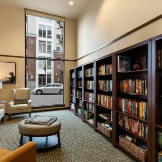 A modern library with tall bookshelves and comfortable seating, featuring large windows that let in natural light.