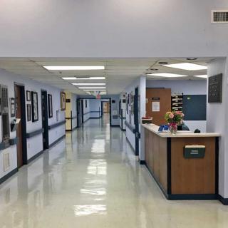 A hospital hallway featuring a reception desk and clean, bright interiors.