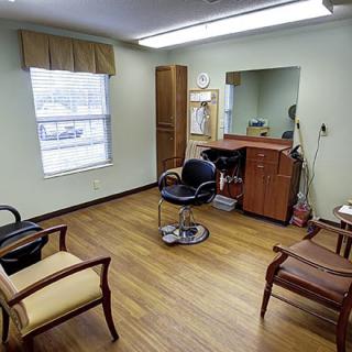 A small hair salon with a barber chair, mirror, and seating area.