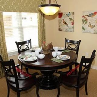 A cozy dining area with a round table set for a meal, surrounded by chairs and decorated with wall art.