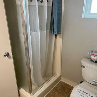 A bathroom with a shower, toilet, and towel.