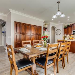 A cozy dining area with a wooden table surrounded by chairs, complemented by modern lighting and elegant cabinetry.