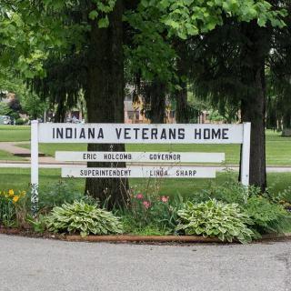 Sign for the Indiana Veterans Home surrounded by greenery.