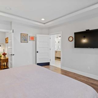 A modern bedroom with a wall-mounted TV, wooden flooring, and contemporary decor.