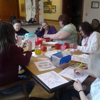 A group of women engaging in an arts and crafts activity at a table indoors.