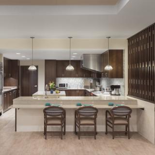 A modern kitchen featuring sleek wooden cabinetry, a spacious countertop, and stylish bar stools complemented by pendant lighting.
