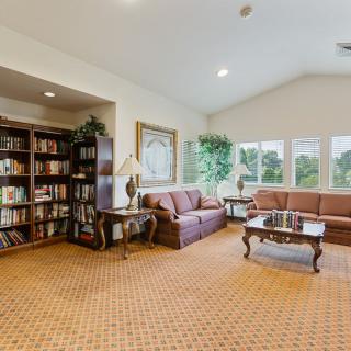 A cozy living room with couches, a bookshelf, and large windows.