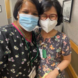Two healthcare professionals posing for a cheerful photo while wearing masks.