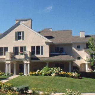 A large residential house with a manicured lawn and colorful garden on a sunny day.