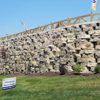 A well-maintained stone wall surrounded by greenery and signage.