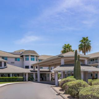 A modern building with an inviting entrance, surrounded by palm trees and well-maintained landscaping.