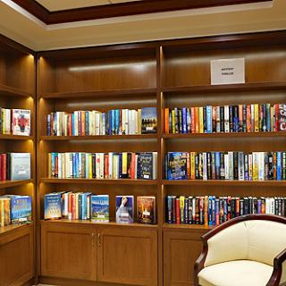 A cozy corner featuring a well-organized bookshelf filled with various books and a comfortable chair.