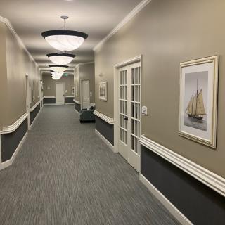 A well-lit hallway with artwork and carpeted flooring.