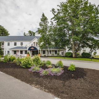 A charming inn surrounded by lush trees and well-maintained gardens.